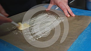 Chef spreading butter on Parchment Paper with a silicone basting brush