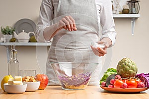 Chef sprinkles salt on salad, stir, in the process of a vegetarian salad with the hand of the chef in the home kitchen.Healthy