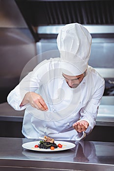 Chef sprinkling spices on dish