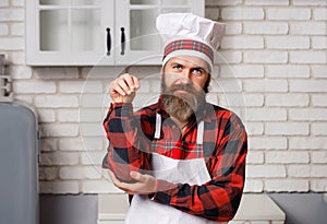 Chef sprinkling spices on dish in commercial kitchen.