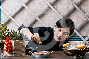 Chef sprinkling spices on dish in commercial kitchen. Gourmet Restaurant