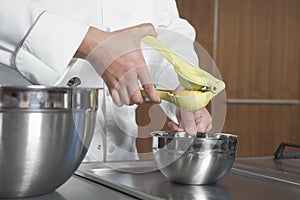 Chef Squeezing Lemon At Counter In Commercial Kitchen