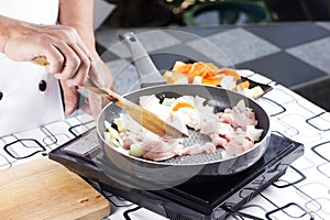 Chef stir-fried slice of pork in the pan for cooking Japanese po