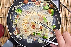 Chef stir fried Spaghetti with tongs