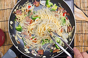 Chef stir fried Spaghetti with tongs