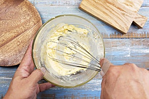 Chef stiring butter and cheese with kitchen whisk on bowl