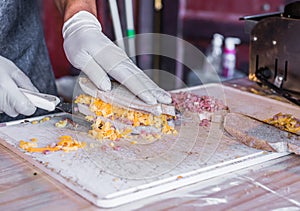 Chef at a street market preparing sandwich with grilled melted cheese and bacon