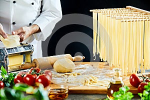 Chef stretching out dough next to rack of noodles