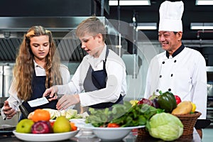 Chef teacher teaches cooking to the group children in class kitchen room