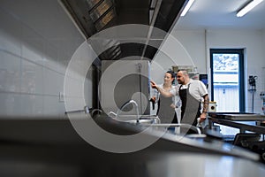 Chef teaching cook how to use combi oven indoors in restaurant kitchen. photo