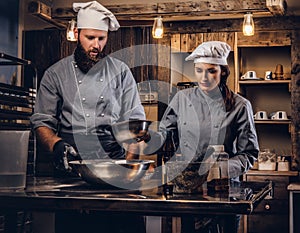 Chef teaching his assistant to bake the bread in the bakery.