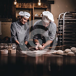 Chef teaching his assistant to bake the bread in a bakery.