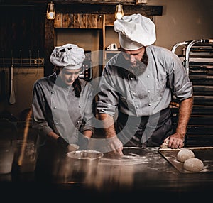 Chef teaching his assistant to bake the bread in a bakery.