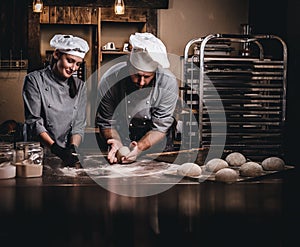 Chef teaching his assistant to bake the bread in a bakery.