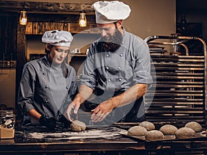 Chef teaching his assistant to bake the bread in a bakery.