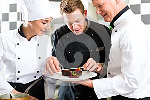 Chef team in restaurant kitchen with dessert