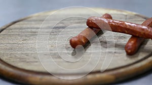 Chef throw sausages on a wooden round board