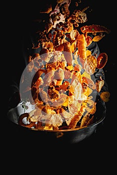 chef throwing snack mix from bowl on black background