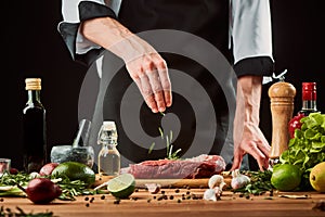 Chef throws rosemary onto raw meat. Uncooked beef steak