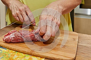 Chef ties the meat with special rope to make meat rolls. French gourmet cuisine