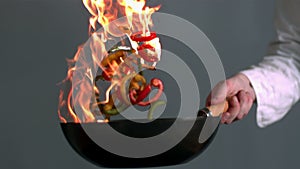 Chef tossing flaming wok of peppers