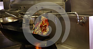 Chef tossing vegetables in a wok over a large flame