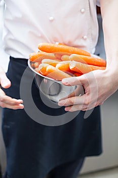 Chef in uniform preparing fresh carrot batons photo