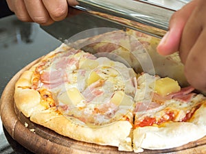 Chef use pizza cutter cutting pizza on wooden tray.