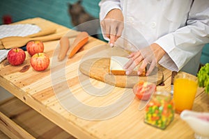 Chef using knife cutting the bread on the chopping board with care in kitchen full of cooking ingredients