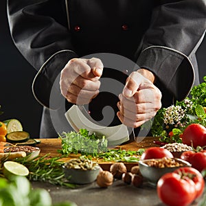 Chef using a mezzaluna knife to chop herbs photo