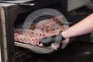 A chef in a very nice pub smokes pork ribs in a large oven.