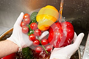 Chef washing bell peppers and cherry tomatoes.