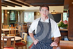 Chef Wearing Whites And Apron Sitting In Restaurant