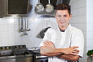 Portrait Of Chef Wearing Whites Standing By Cooker In Kitchen photo