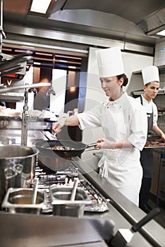Chef, woman and frying pan with sauce in kitchen, catering service and prepare food for restaurant fine dining photo