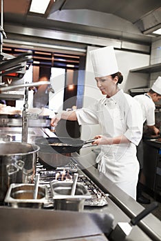 Chef, woman and frying pan with sauce in restaurant kitchen, catering service and prepare food for fine dining photo