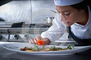Chef woman garnishing flower in dish at kitchen