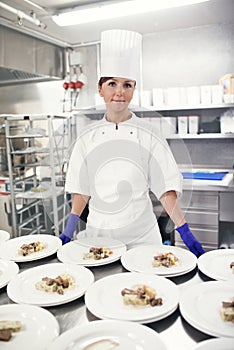 Chef, woman and kitchen portrait with food, restaurant and gourmet meal prep and serving. Smile, catering service and