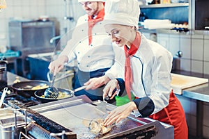 Chef woman and man cooking together in a restaurant kitchen