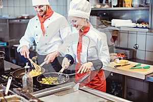 Chef woman and man cooking together in a restaurant kitchen