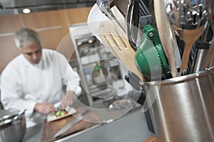 Chef Working With Utensil Holder In Foreground