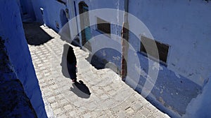 Chefchaouen, Tetouan, Morocco - July 28, 2022: Street scene with a traditionally dressed woman.
