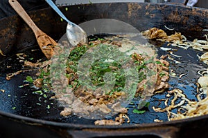 Cheff cooking delicious liver and onion dish in a large pan.