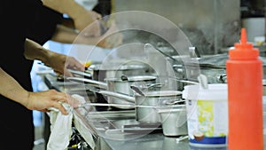 Chefs cook standing at the stove, close-up. Industrial kitchen close-up. The hands of the cooks close-up. Stainless