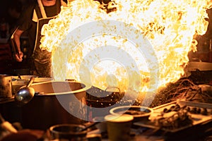 The chefs are cooking with fire over the pan, at street food dining options in all of Bangkok, Yaowarat road or Chinatown Thailand