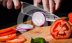 Chefs hands chopping onion on wooden board