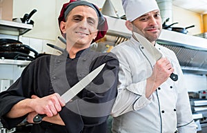 Chefs posing with knife in their restaurant kitchen