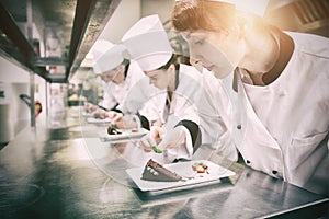 Chefs standing in a row garnishing dessert plates photo