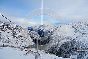 Cheget skiing chairlift. Snowy peaks of Caucasian Mountains in the clouds blue sky