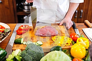 Cheif cook coooking meat and salad with fresh vegetables